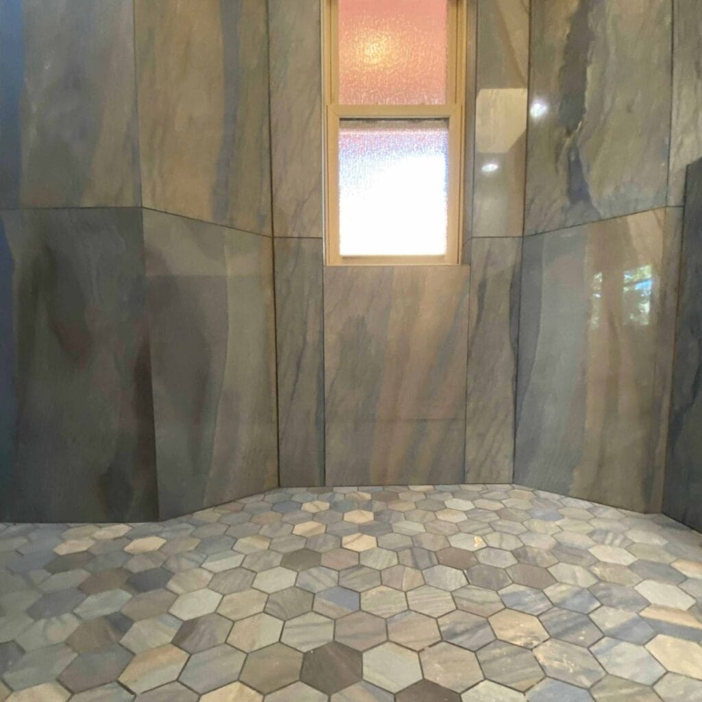 A Sedona Style bathroom interior by Sedona Interior Designer Dana Cavanaugh, featuring natural stone walls and hexagonal tile flooring in earthy tones.